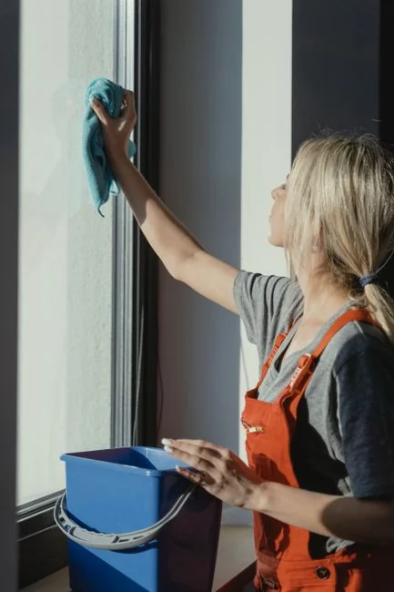 who-we-are A woman carefully wraps a sofa in protective material while packing boxes in a bright room.